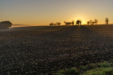 Obraz premium Beautiful sunrise over the mountains in the area of still shaded farmland