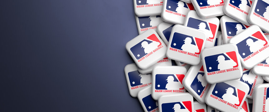 Logos of the American Baseball League MLB (Major League Baseball) on a heap on a table.