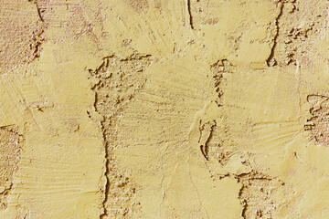 Beige or yellow stucco and cement exterior of building or house or home in late afternoon sun light with texture ridges