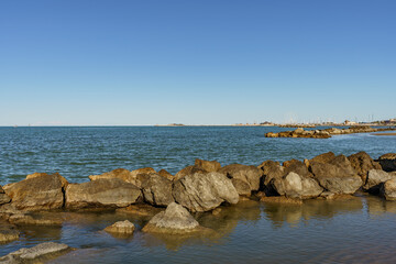 Fototapeta na wymiar A band of natural rocks forming a natural breakwater protecting the sea beach