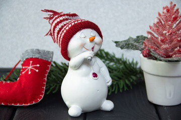 Silver background. New Year's decor. Snowman. Warm hat. Christmas tree. Red shoe.