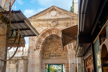 The arched entrance gate to the Ayyubid Mosque of Omar, an Islamic place of worship inside the Old City of Jerusalem, Israel opposite the Holy Sepulchre Church. - obrazy, fototapety, plakaty
