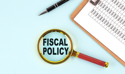 FISCAL POLICY text on magnifier with clipboard on blue background