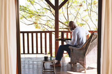 African american man playing guitar on veradna outside log cabin