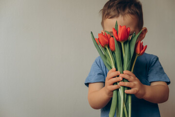 a child sniffs a bouquet of red tulips
