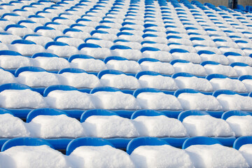 Naklejka premium the snow-covered seats of the stadium stands