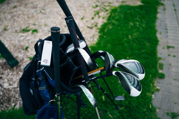 Golf ball and golf club in bag on green grass
