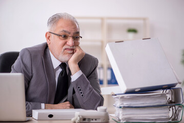 Old male employee eating pizza in the office