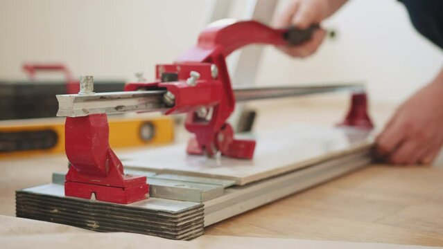 Close-up of a work tool using manual cutting equipment for laying, processing ceramic tiles. Interior finishing worker, tiler or handyman, using manual tile cutter