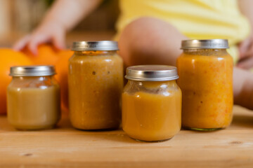baby vegetable and fruit puree in jars in the kitchen, mockup. Baby food, space for text. Jars of baby food on a wooden table