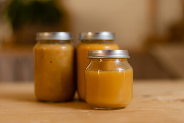 baby vegetable and fruit puree in jars in the kitchen, mockup. Baby food, space for text. Jars of baby food on a wooden table