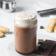 Mocha latte with whipped cream in a can shaped glass, iced mocha with foam and chocolate syrup