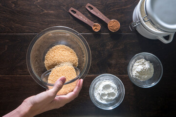 Cropped image of woman pouring brown sugar in bowl on wooden table