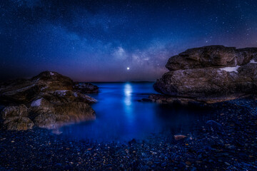 Coastline with rock formations under Milky Way and Venus