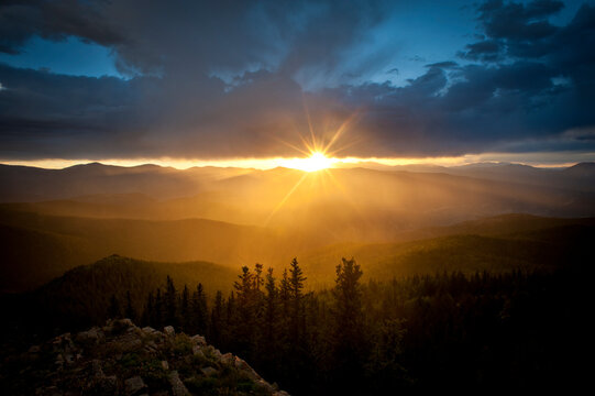 Setting sun lighting up rain in a mountain valley.  Cuchara, Colorado, United States.