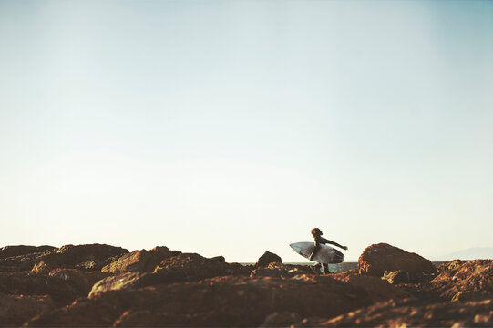 Surfer runs over rocks to find waves