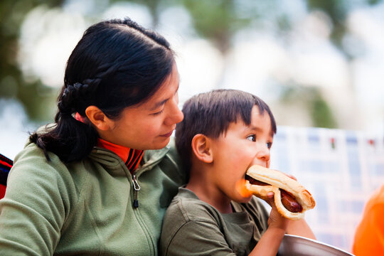 Mother holding son eating hot dog