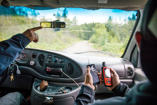 Mountain guides navigate using GPS in 4x4 van.