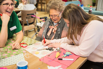 Senior women with girl and nurse doing craft activity at rest home
