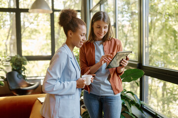 Two young business woman enjoying pleasant conversation in coworking space