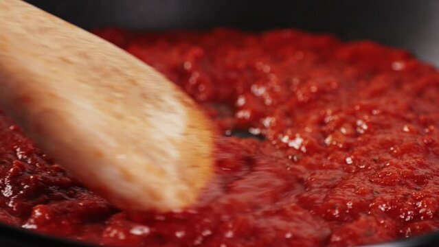 Classic homemade Italian tomato sauce with basil for pasta and pizza in the pan. Chef cooking traditional Italian food.