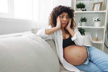 Pregnant woman headache lies at home on the couch fatigue and heaviness in the last month of pregnancy before childbirth, motherhood difficulties