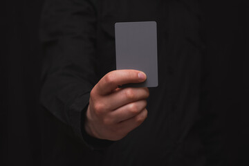 man holding gray card on a black background, for commercial or financial theme use.