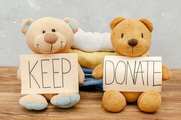 Stack of old baby children clothes,teddy bear toys,sorted into Keep and Donate...