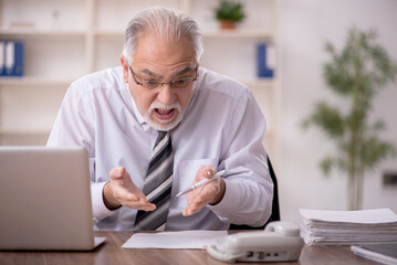 Fototapeta premium Old male employee working in the office