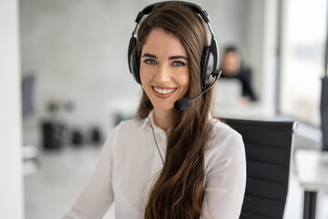 Close up portrait of service desk consultant woman talking using hands-free headphones with...