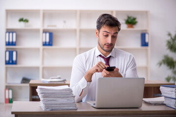Obraz premium Young male employee and too much work at workplace