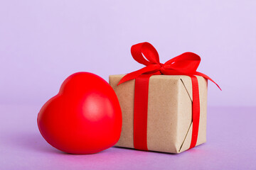 gift box with red bow and red heart on colored background. Perspective view. Flat lay