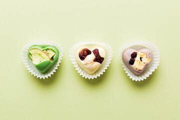 chocolate sweets in the form of a heart with fruits and nuts on a colored background. top view with space for text, holiday concept