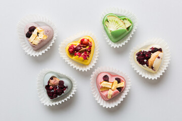 chocolate sweets in the form of a heart with fruits and nuts on a colored background. top view with space for text, holiday concept