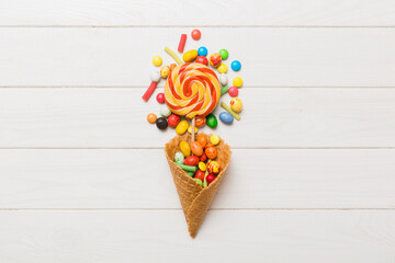 waffle cone full of assorted traditional candies falling out on colored background with copy space. Happy Holidays sale concept