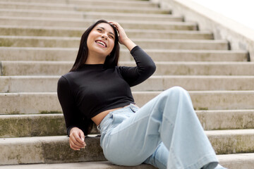 Girl with giggling eyes and head touching head sitting on a ladder.