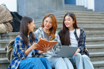 Attractive asian college student using laptop and tablet studying with group of friends together with english language classroom, social media and education concept.
