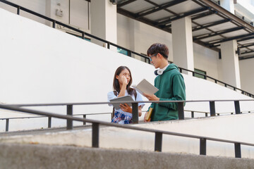 Fototapeta premium Attractive asian college student using laptop and tablet studying with group of friends together with english language classroom, social media and education concept.