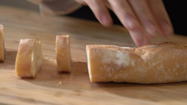 The professional chef's skilled hands move smoothly and confidently as they slice through the thick slices of French toast, the sharp blade of their knife glinting in the light.
