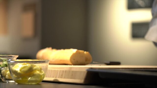 The professional chef's skilled hands move smoothly and confidently as they slice through the thick slices of French toast, the sharp blade of their knife glinting in the light.
