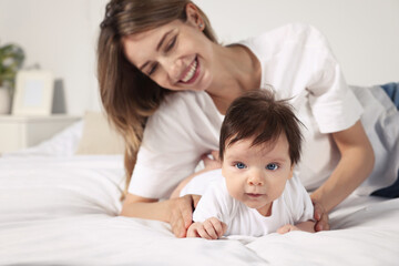 Cute little baby and mother on cosy bed in room