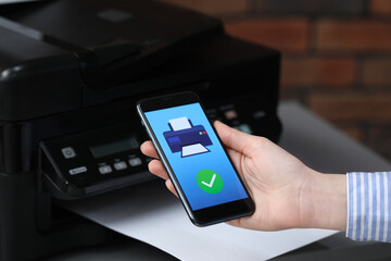 Man using printer management application on mobile phone indoors, closeup. Image on device screen.