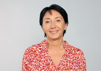 Portrait of smiling senior woman on light grey background