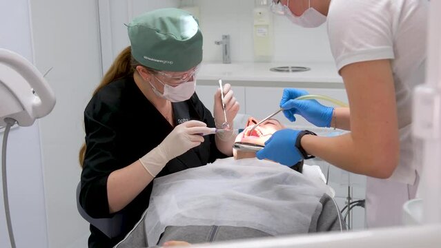 hard tooth extraction, tooth extraction tools Gracie curette, piezo scaler, piezo scaler attachment, piezo scaler wrench, luxator woman doctor dentist removes a man patient tooth heavy easy extraction