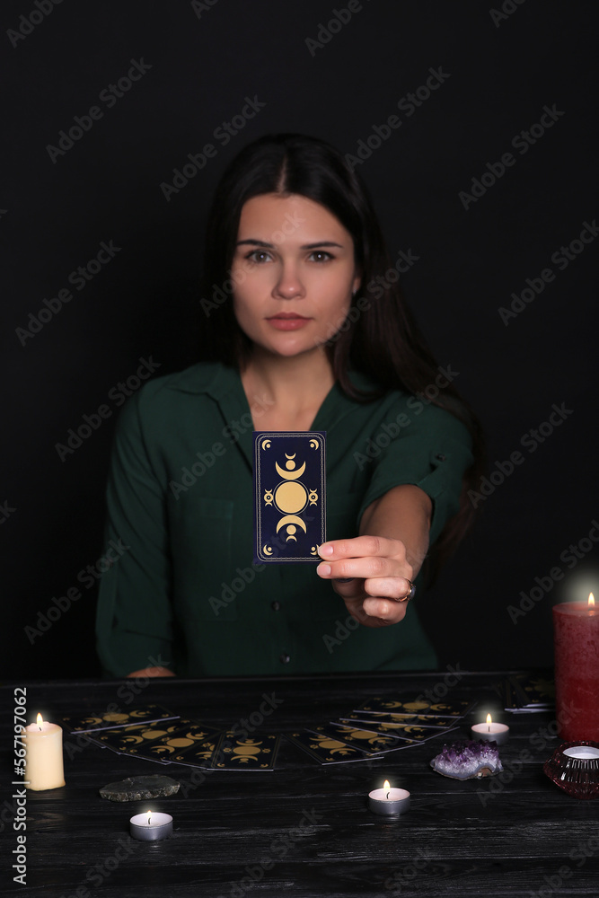 Sticker soothsayer predicting future at table against black background, closeup. focus on tarot card