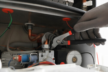 Man repairing gas boiler with waterpump plier, closeup