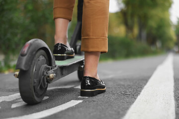 Businesswoman with modern electric kick scooter on city street, closeup. Space for text