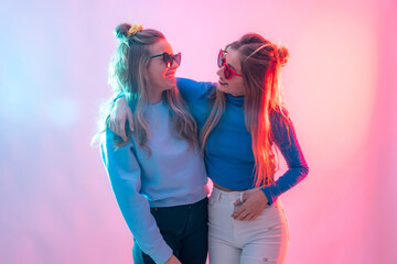 Two young blonde caucasian women dancing in disco, portrait smiling and embracing