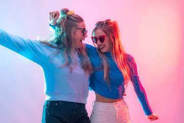 Two young blonde caucasian women dancing in disco, smiling and having fun at party