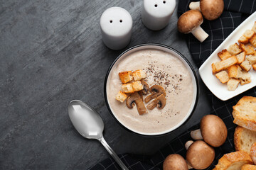 Delicious cream soup with mushrooms and croutons on black table, flat lay. Space for text